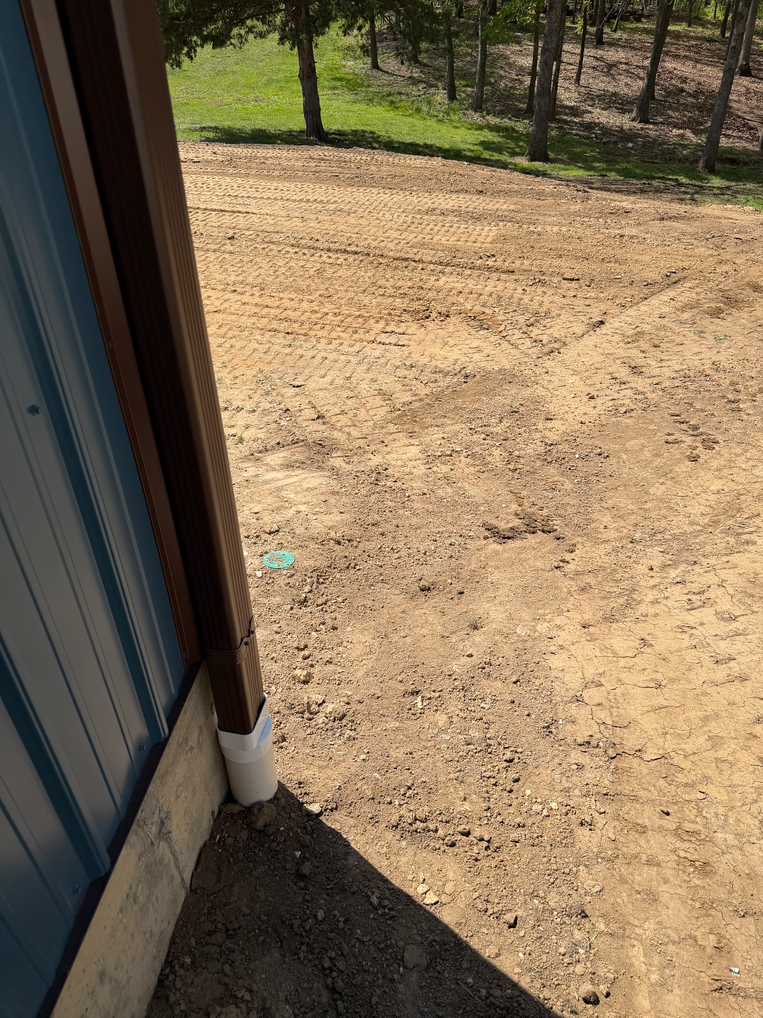 Stabilized yard with new downspouts and leveled pool pad behind shed after grading