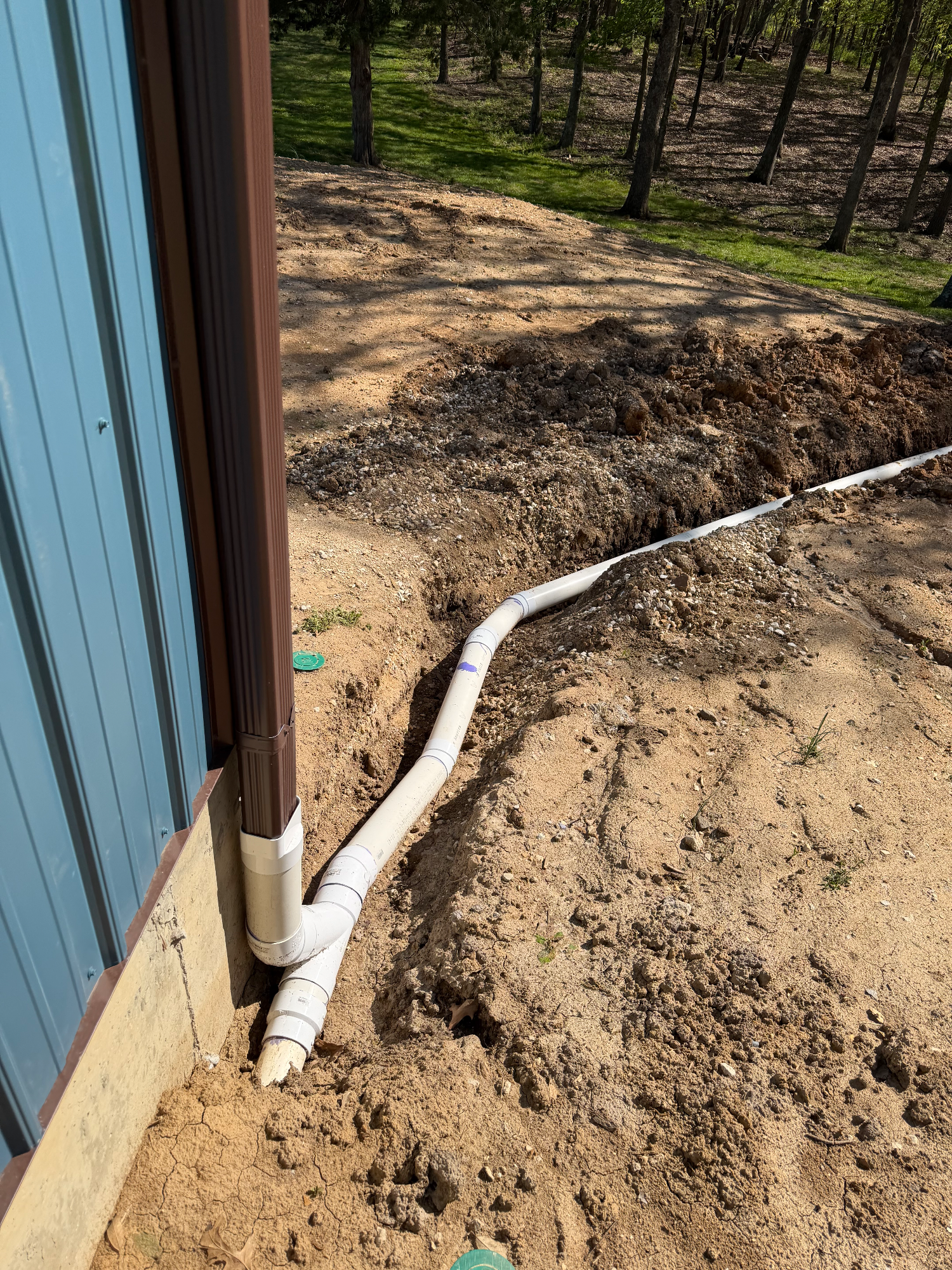 Eroded yard behind shed with damaged downspouts before drainage work in Winfield