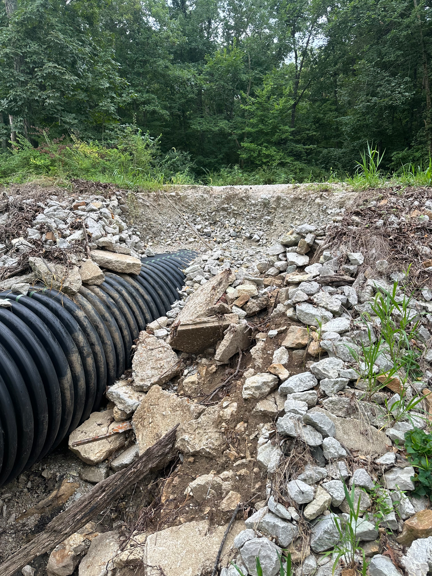 Washed-out gravel driveway with eroded hillside and failed culvert after heavy rain