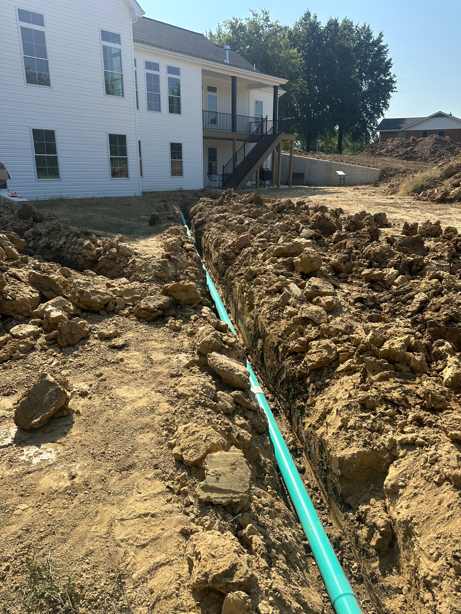 Bare soil along foundation of new house in Eolia before downspout drainage installed